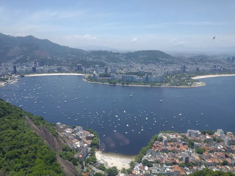 Vista do alto do Morro da Urca: a enseada de Botafogo, barcos ancorados e os prédios do bairro entre morros.